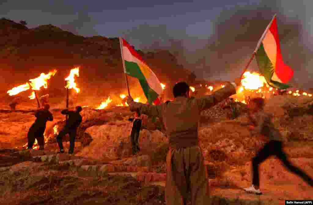 Iraqi Kurds wave Kurdish flags and hold burning torches as they walk up a mountain during a gathering to show support for the upcoming independence referendum and encourage people to vote in the town of Akra, some 500 kilometers north of Baghdad. (AFP/Safin Hamed)