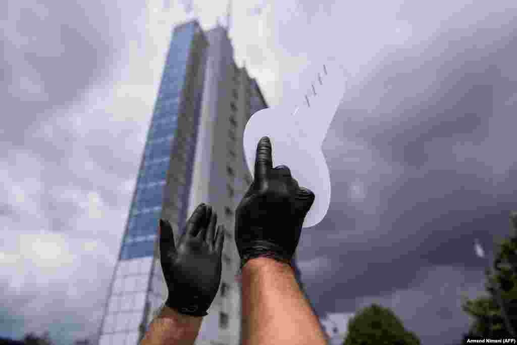 A man holds a cardboard key during a protest against government measures to fight a resurgence of the coronavirus in front of the government building in Pristina. (AFP/Armend Nimani)