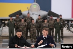 Emmanuel Macron și Volodimir Zelenski semnează un acord la baza aeriană Villacoublay, lângă Paris, Franța, 17 noiembrie 2025.