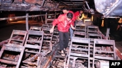 Volunteers search for bodies inside a burnt out passenger bus after it collided with an oil tanker near Karachi early on January 11.