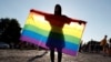 A demonstrator holds an LGBT flag during a protest against the law in Budapest in June.