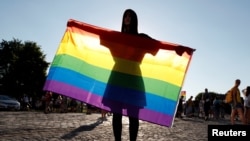 A demonstrator holds an LGBT flag during a protest against the law in Budapest in June.