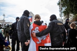 Riot police detain a protester, draped in an old Belarusian national flag, on Independence Square in Minsk late last month.