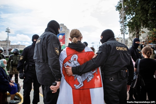 Protestor with Belarusian flag is escorted by the police.