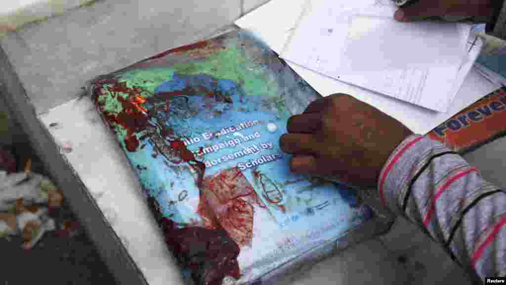 A rescue worker inspects blood-stained paperwork that was being carried by Nasima Bibi, who was shot and killed by gunmen in Karachi on December 18. (Reuters/Athar Hussain)