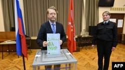 Russia's liberal Yabloko party leader Nikolai Rybakov casts his ballot with a marker writing "For peace" during Russia's parliamentary election at a polling station in Saint Petersburg on September 20.