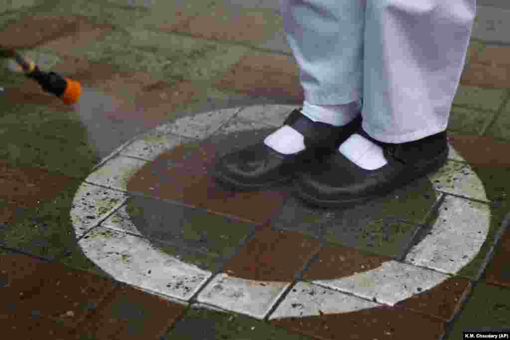 A worker sprays sanitizer on the shoes of a student upon her arrival at a school in Lahore, Pakistan. Pakistani authorities have started to reopen schools in phases despite a steady increase in deaths and infections from the coronavirus. (AP/K.M. Chaudary)