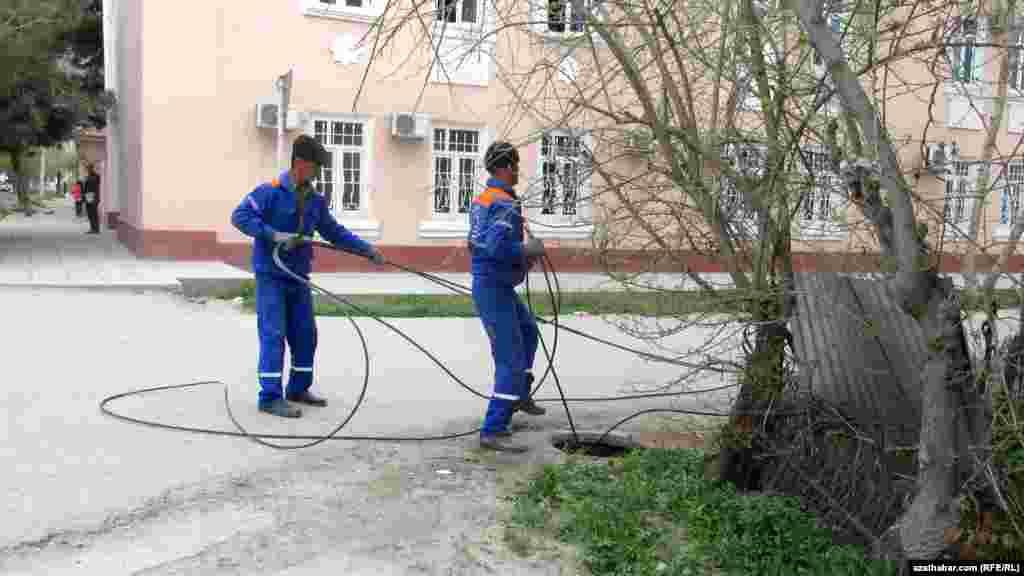 Aşgabadyň köçeleriniň birinde işgärler kabel liniýalaryny geçirýärler.