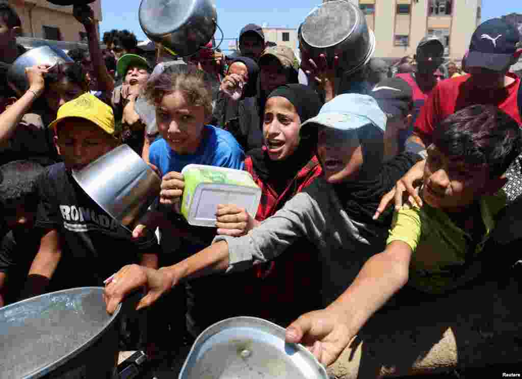 Palestinieni care încearcă să obțină alimente de la o fundație caritabilă, la Nuseirat, în centrul Fâșiei Gaza, pe 20 iulie.