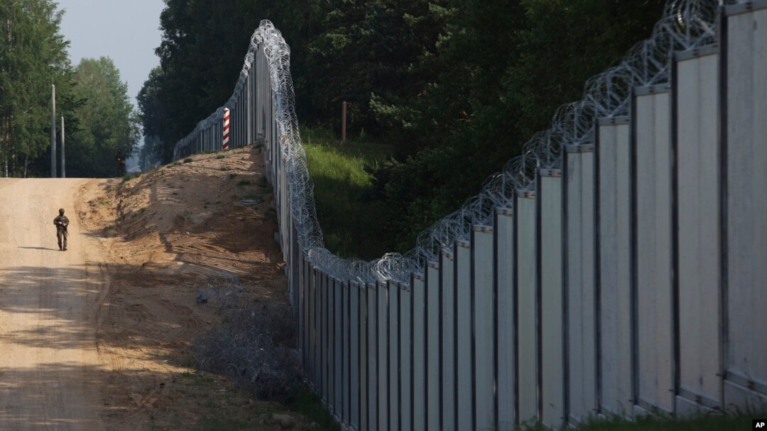 A Polish border guard patrols the area of a newly built metal wall on the border between Poland and Belarus near Kuznica in June 2022.