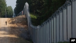 A Polish border guard patrols the area of a newly built metal wall on the border between Poland and Belarus near Kuznica in June 2022.