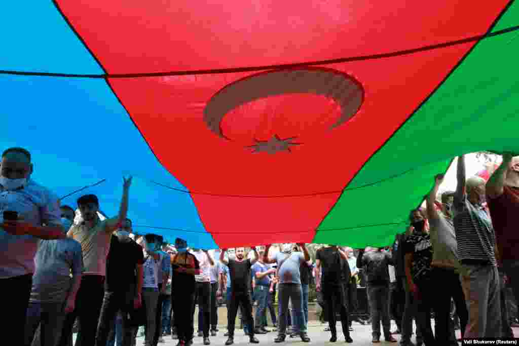 Azerbaijani mourners carry their nation&#39;s flag during the funeral march for Gashimov and Mirzayev.