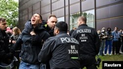 Rendőrök szednek ki egy tüntetőt a palesztinbarát emberláncból Berlinben, a Freie Universität (FU) udvarán 2024. május 7-én