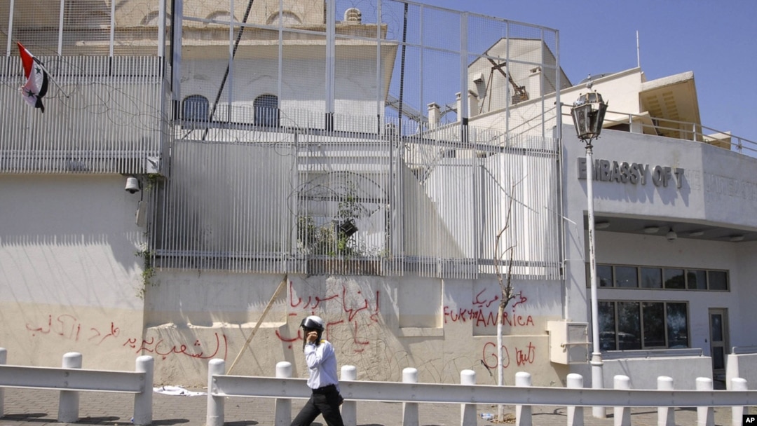 A policeman walks in front of the damaged U.S. embassy after pro-government protesters attacked the embassy and raised a Syrian flag on the compound in Damascus