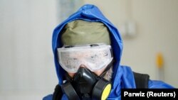 A health worker wearing a protective suit sprays disinfectant outside of a building during an awareness campaign for coronavirus disease (COVID-19), in the eastern city of Jalalabad on March 19.