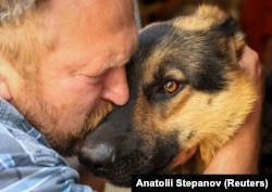 A local of Druzhkivka bids farewell to his dog as he prepares to evacuate his home on June 20. The dog was handed to an animal welfare charity.