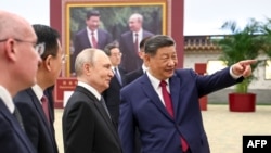 Президент РФ Володимир Путін (ліворуч) і президент Китаю Сі Цзіньпін оглядають фотовиставку, присвячену російсько-китайським відносинам, Пекін, Китай, 20 травня 2026 року