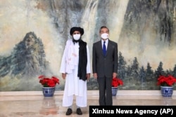 “Талибандын” негиздөөчүсү Молдо Абдул Гани Барадар (солдо) менен Кытайдын тышкы иштер министри Ван И Тяньцзиндеги жолугушууда. 28-июль, 2021-жыл