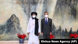 Taliban co-founder Mullah Abdul Ghani Baradar (left) and Chinese Foreign Minister Wang Yi pose for a photo during their meeting in Tianjin on July 28.