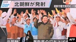 Sjeverna Koreja tvrdi da je uspješno postavila izviđački satelit 'Malligyong-1' u orbitu. Na fotografiji su pješaci pored ekrana na kojem je prikazan lider Sjeverne Koreje Kim Jong Un kako slavi lansiranje satelita; okruga Akihabara u Tokiju 22. novembra 2023.