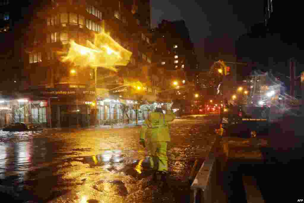 A Con Edison worker walks through the flood waters on the corner of 33th Street and 1st Street in front of NYU Langone Medical Center in Manhattan.