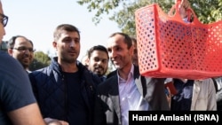 Former Iranian Vice President Hamid Baghaei (holding bag) greets supporters after his trial on October 22.
