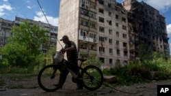 Місцевий житель іде з велосипедом повз будинок, зруйнований російською авіацією. Торецьк, 28 червня 2024 року
