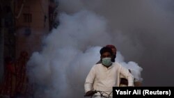 As a preventive measure against the coronavirus health workers on motorbike fumigate along a street in the southern Pakistani city of Hyderabad on March 15