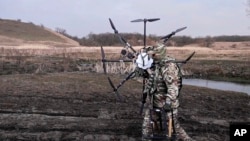 Un militar neidentificat cară o dronă în Ucraina.