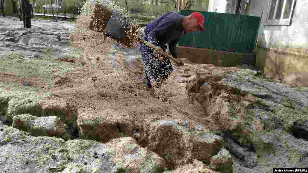 Суу ташкынынан кийин короосун тазалап жаткан тургун. Нөшөрлөгөн жаан учурунда калың мөндүр да жааган.&nbsp;