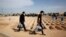 Iranian men walk past empty, prepared graves at Behesht Zahra, Tehran's main cemetery.