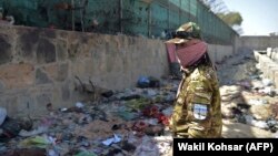 A Taliban fighter stands guard at the site of one of the August 26 suicide bombing at Kabul airport.