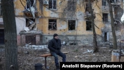 Чоловік сидить на лавці біля багатоквартирного будинку, пошкодженого внаслідок російського удару, Костянтинівка, Донецька область, 7 грудня 2025 року