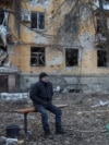 Чоловік сидить на лавці біля багатоквартирного будинку, пошкодженого внаслідок російського удару, Костянтинівка, Донецька область, 7 грудня 2025 року