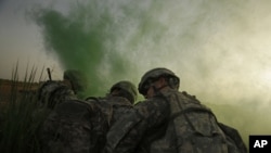 U.S. Army soldiers shield themselves from rotor wash as they use green smoke to mark a landing zone for a Blackhawk helicopter after an operation to disrupt weapons smuggling in Istaqlal, Iraq, in August.