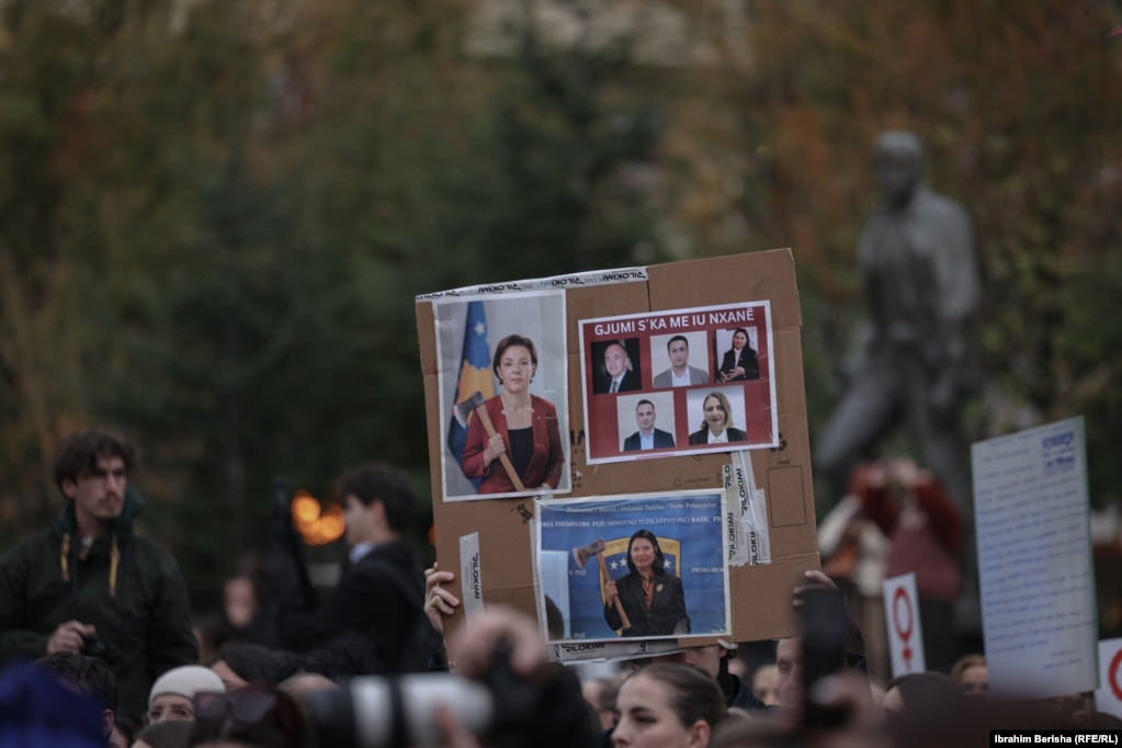 Në këtë fotografi protestuesit mbajnë imazhe të ministres së Drejtësisë, Donika Gërvalla, e ilustruar me sëpatë në dorë, si dhe të zyrtarëve të tjerë të drejtësisë.Protestuesin kërkojnë që Gërvalla të japë dorëheqje. 