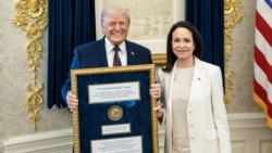 Președintele SUA, Donald Trump, ținând medalia Premiului Nobel pentru Pace primită de la lidera opoziției venezueliene, Maria Corina Machado, la Casa Albă, pe 15 ianuarie 2026 