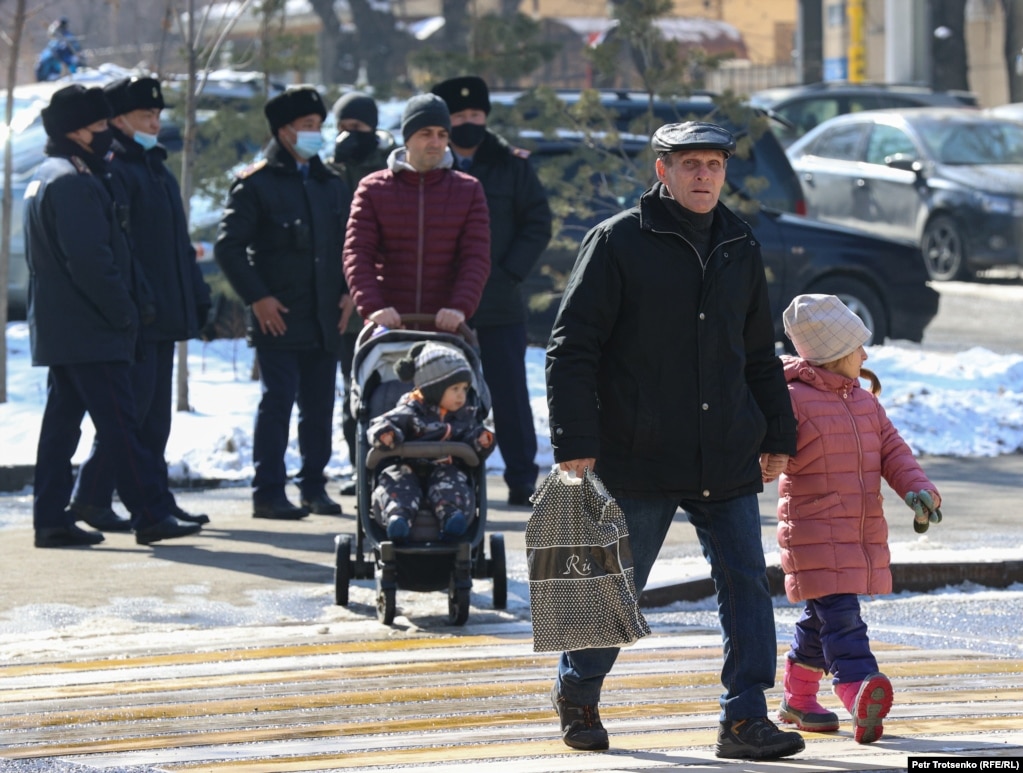 Люди проходят мимо сотрудников полиции неподалеку от Центрального парка. Алматы. 28 февраля 2021 года