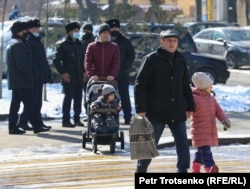 Люди проходят мимо сотрудников полиции неподалеку от Центрального парка. Алматы. 28 февраля 2021 года