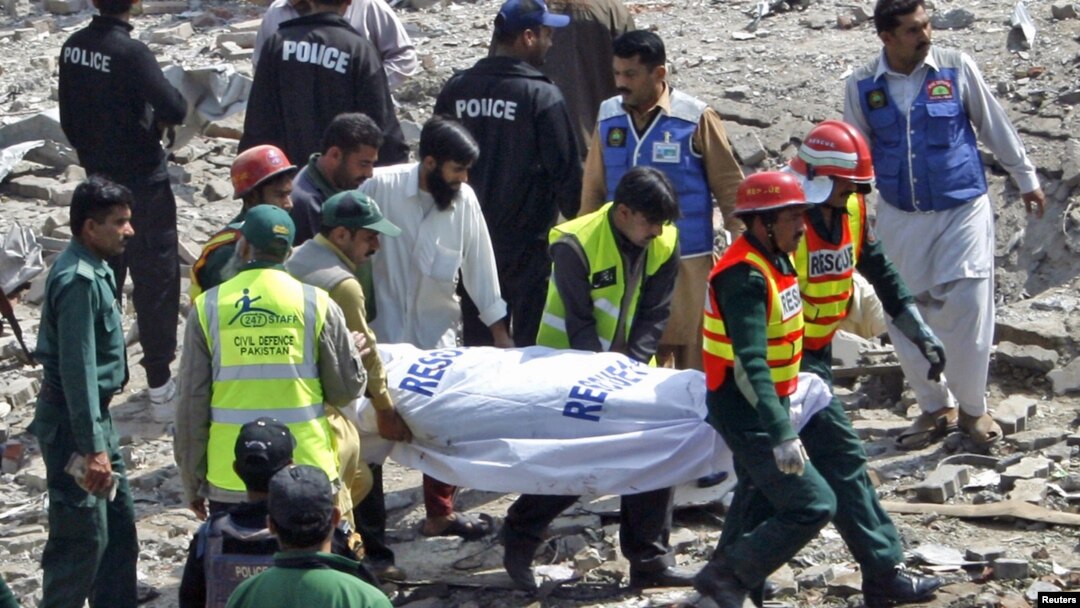 Rescue workers carry a body from the site of a bomb explosion at a filling station in Faisalabad today.
