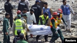 Rescue workers carry a body from the site of a bomb explosion at a filling station in Faisalabad today.