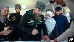 Aymani Kadyrova (center right) stands next to her son, Chechen strongman Ramzan Kadyrov, as he registers at a polling station in the Chechen town of Tzentoroi, Russia, in 2016. 