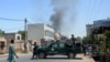 Afghan security personnel secure a road as smoke billows from the site of a suicide attack in Jalalabad on July 31.