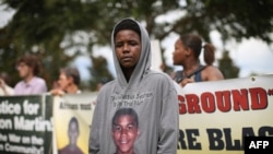 Un demonstrant în fața tribunalului din Florida cu imaginea lui Trayvon Martin pe tricoul lui