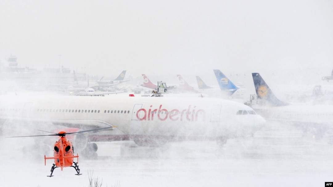 A helicopter lands next to an Air Berlin plane at the airport of Duesseldorf, Germany, one of many airports struggling to cope with the weather.