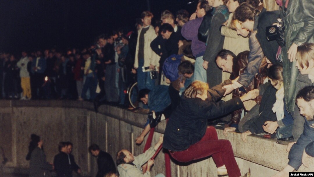 10 noiembrie 1989. Est-germani ajutați de vest-germani să se urce pe zidul care despărțea Berlinul. Zidul a început să fie dărâmat din 9 noiembrie 1989. AP Photo/Jockel Finck
