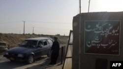 A Pakistani security officer searches a car at a checkpoint in Pishin, Baluchistan, in July 2011.