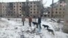 Oameni cară sticle cu apă pe lângă clădiri rezidențiale avariate în orașul Avdiivka din regiunea ucraineană Donețk, controlată de Rusia. Imagine preluată dintr-un videoclip furnizat de Ministerul rus al Apărării pe 20 februarie 2024.