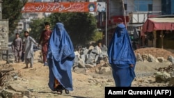 Burqa-clad Afghan women walk past a construction site in Kabul on September 8.