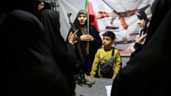 A member of Iran's military trains people how to use a use a gun in Tehran on May 18 amid signs of growing public militarization in the country. 